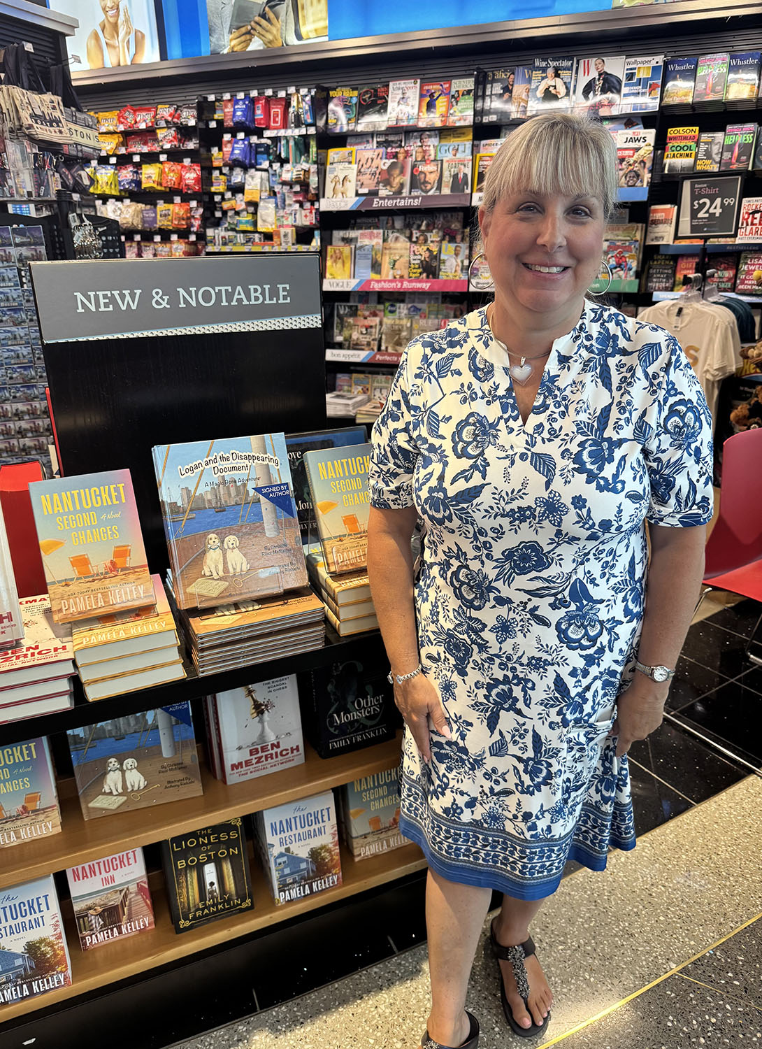 Christine Ricci-McNamee stands next to her books at Logan Airport