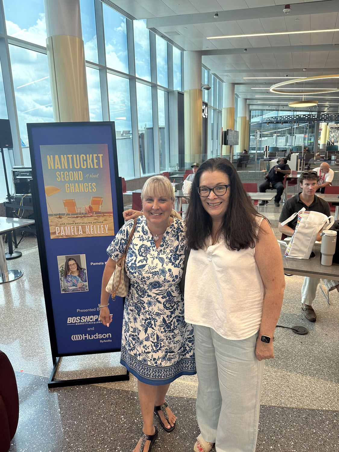 Christine Ricci-McNamee stands next to her books at Logan Airport